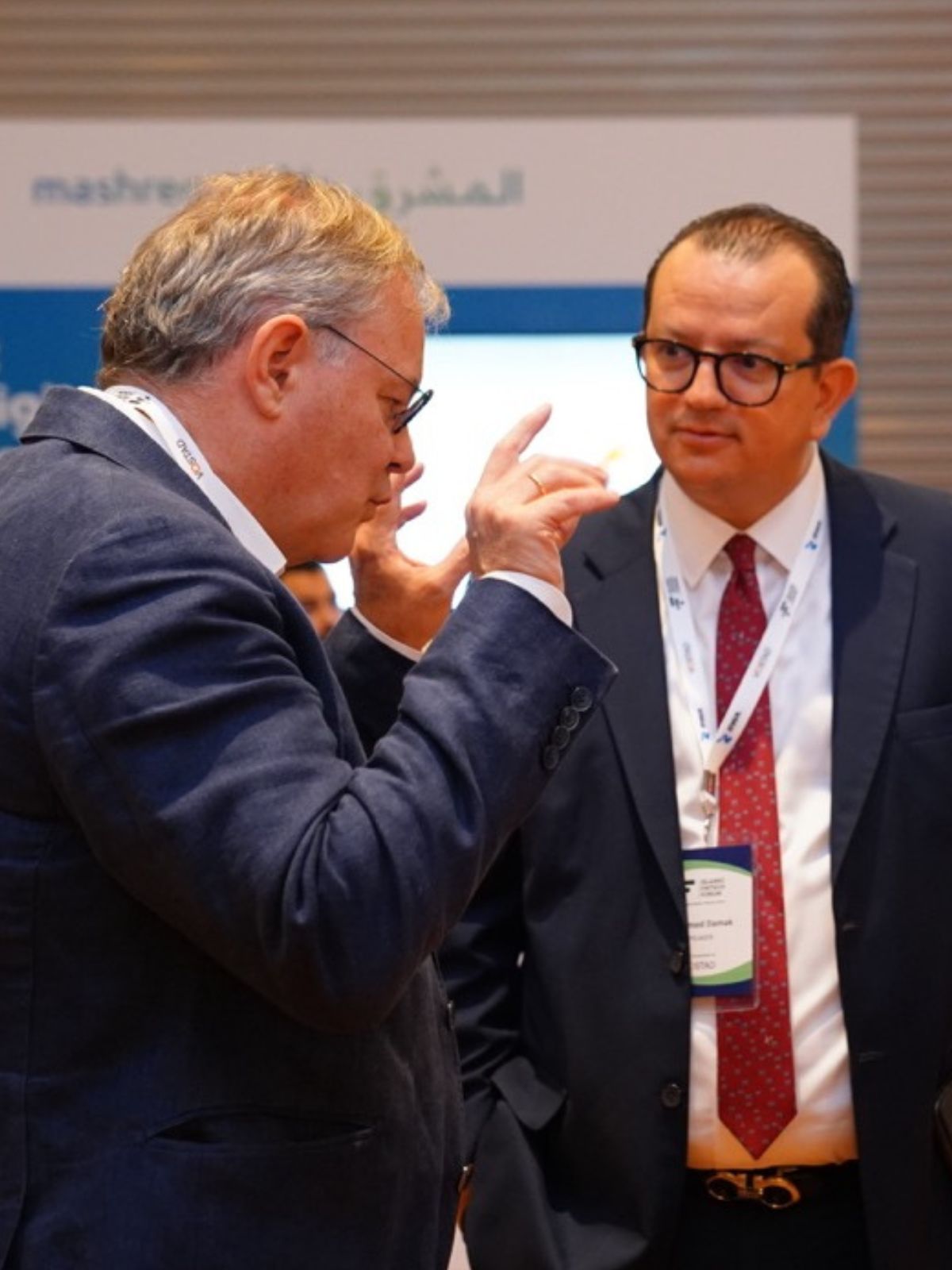 Two executives in close conversation; one makes a point with a raised hand.
