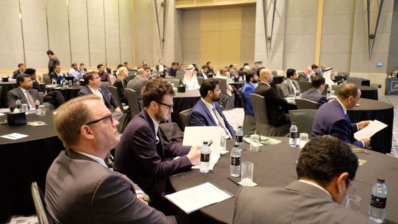 Senior executives at round tables read papers and take notes during a working session.
